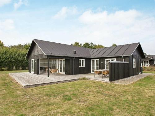 a house with a black roof and a deck at 8 person holiday home in Nysted in Nysted