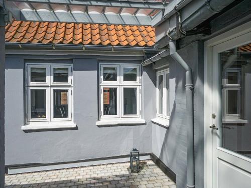 uma casa com três janelas e uma porta em 5 person holiday home in R nne em Rønne