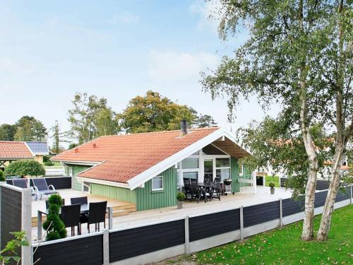 オテルプにある6 person holiday home in Otterupの赤い屋根と白い柵の緑の家