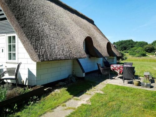 a thatch roofed house with a table and chairs at 6 person holiday home in Asperup in Asperup