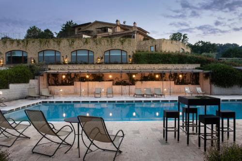 un patio con sillas y una mesa junto a la piscina en Altarocca Wine Resort Adults Only en Orvieto