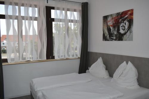 um quarto com 2 camas brancas e uma janela em Motel Schönefeld em Großziethen