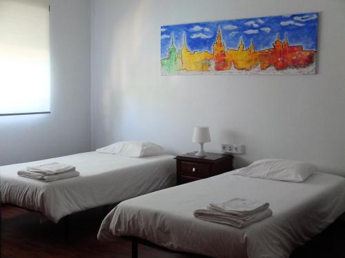 two beds in a room with a painting on the wall at House near Fontelo in Viseu