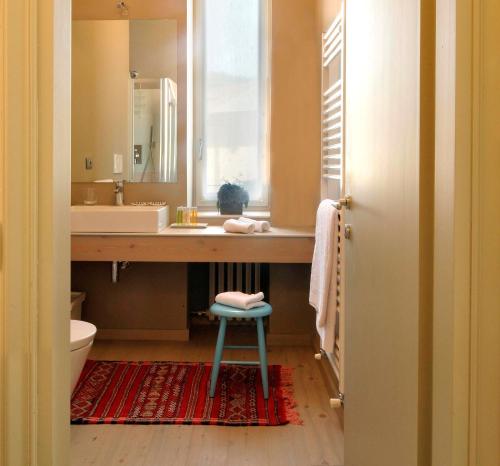 ein Badezimmer mit einem Waschbecken, einem Spiegel und einem Stuhl in der Unterkunft Sopra Il Posta in SantʼOmobono Imagna