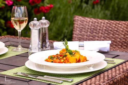 a plate of food on a table with a glass of wine at Pałac Pakoszów Schlosshotel Wernersdorf in Jelenia Góra