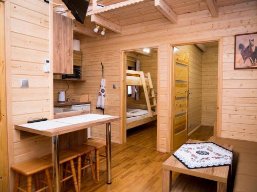 a wooden cabin with a kitchen and a bunk bed at Radawa - Domki przy Stadninie in Radawa