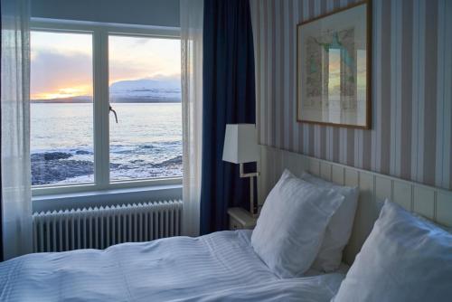 a bedroom with a bed and a large window at Havgrim Seaside Hotel 1948 in Tórshavn