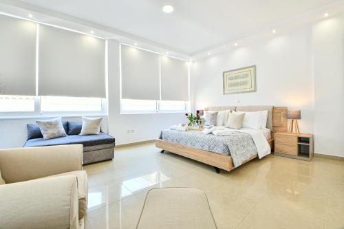 a bedroom with a bed and a couch and windows at AEOLIS SUITES in Athens