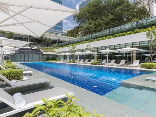 a swimming pool with chairs and umbrellas next to a building at Four Seasons Hotel Bengaluru at Embassy ONE in Bangalore