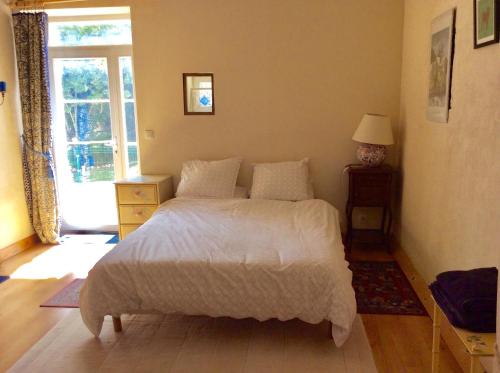 1 dormitorio con cama blanca y ventana en Gite de Pete, en Le Buisson