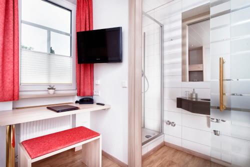 a small bathroom with a red bench and a television at TOP Hotel Goldenes Fass in Rothenburg ob der Tauber