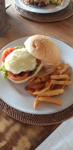 a plate with a hamburger and french fries on a table at Atres Villa in Munduk