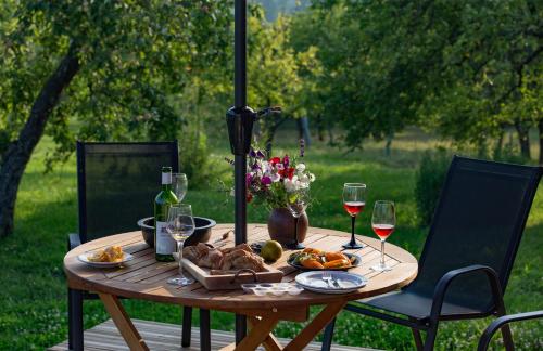 een houten tafel met een bord eten en wijnglazen bij Mednieki Kalvene in Krusāti
