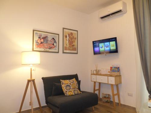ein Wohnzimmer mit einem Stuhl und einem Flachbild-TV in der Unterkunft GELSO HOME in Neapel