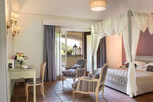 una camera con letto a baldacchino e tavolo e sedie di Altarocca Wine Resort Adults Only a Orvieto