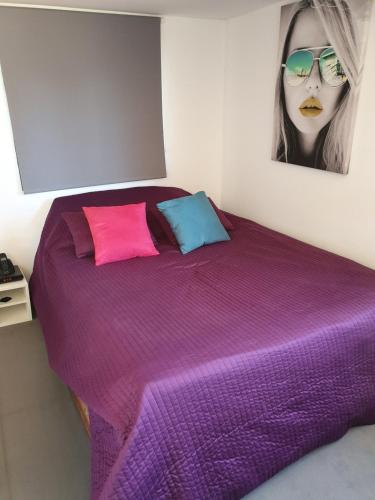 - une chambre dotée d'un lit violet avec des oreillers roses et bleus dans l'établissement LOFT 3 PERS PROCHE CIRCUIT PAUL RICARD, à Signes