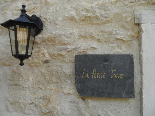 a street light attached to a stone wall with a sign at La Petite Tour in Carlux