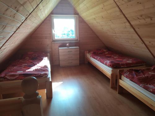 ŁabowaにあるChatki u Natkiのベッド2台と窓が備わる屋根裏部屋です。