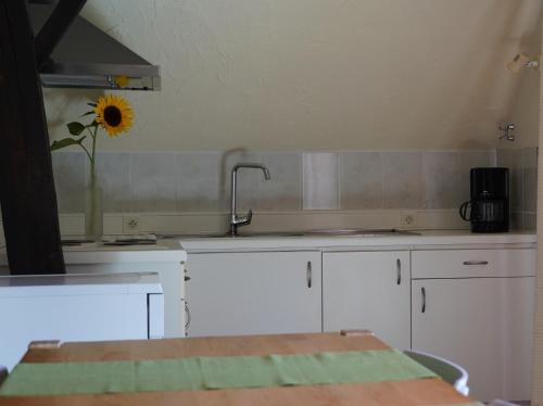 una cocina con fregadero y un girasol en la pared en Rootmolen, en Kortessem