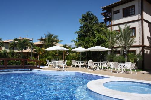 uma piscina com cadeiras e guarda-sóis ao lado de um edifício em Apartment Terraces Porto Das Baleias na Praia do Forte