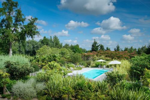 une piscine dans un jardin avec des plantes dans l'établissement Château Grattequina Hôtel, à Blanquefort