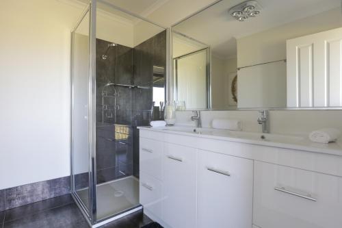 a white bathroom with a shower and a sink at Harmans Lodge Private Rural Escape in Wilyabrup
