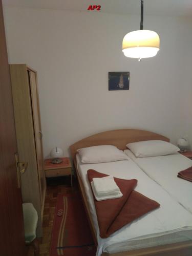 a bedroom with a bed with white pillows and a light at Apartments Šudić in Njivice