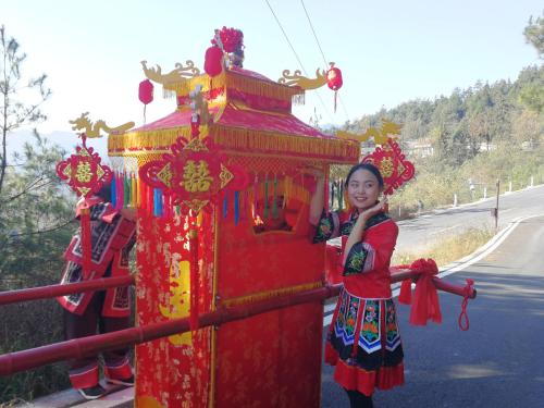 a young girl standing next to a red structure at Dayong Antique Feature Resort in Zhangjiajie