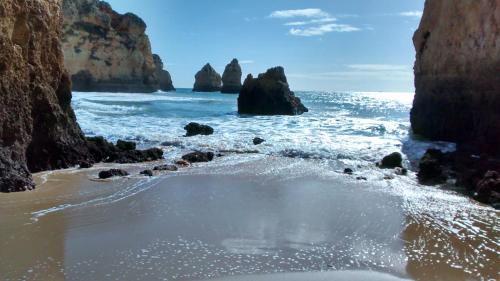 a beach with some rocks in the ocean at Apartamento Vila Marachique in Alvor