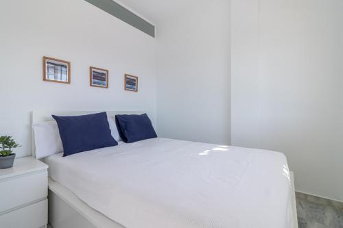un lit blanc avec des oreillers bleus dans une chambre dans l'établissement Holidays Port Ducal 3 Jacuzzi, à Empuriabrava
