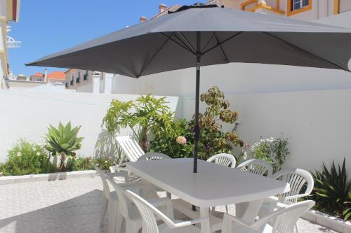 a white table and chairs with an umbrella at Baleal Holiday House in Baleal