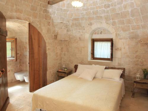 a bedroom with a large bed in a stone wall at Pietraluce in Alberobello