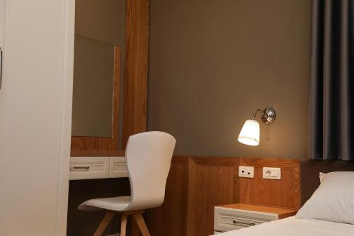 a bedroom with a white chair in front of a bed at Hotel Romeo in Korçë