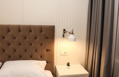a bedroom with a bed with a headboard and a lamp at Hotel Romeo in Korçë