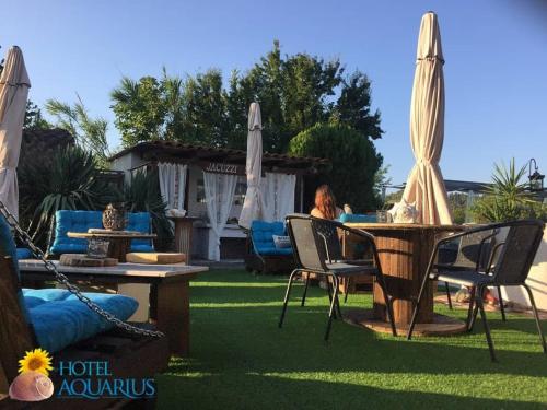 a woman sitting at a table with chairs and umbrellas at Aquarius Hotel in Fourka