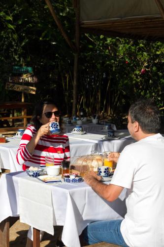 um grupo de pessoas sentadas à mesa comendo comida em Pousada Catarina em Paraty