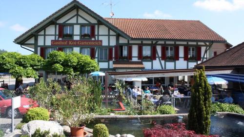 a building with a restaurant with a fountain in front of it at Hotel Restaurant Koi-Gartenteich in Hausernmoos