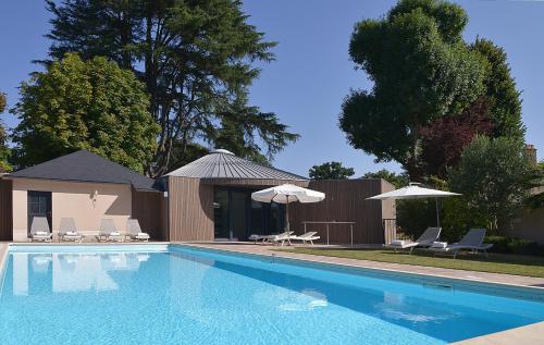 a swimming pool with two umbrellas and two chairs at Logis Le Parc Hotel & Spa in Château-Gontier