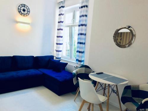 a living room with a blue couch and a table at Apartament Pod Żaglami in Gdynia