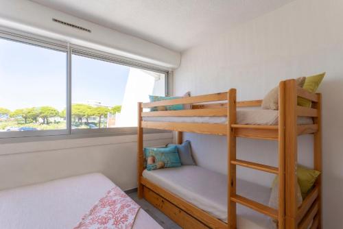 une chambre avec deux lits superposés et une fenêtre dans l'établissement Superbe Marina Spacieuse en face de la Plage!, au Grau-du-Roi