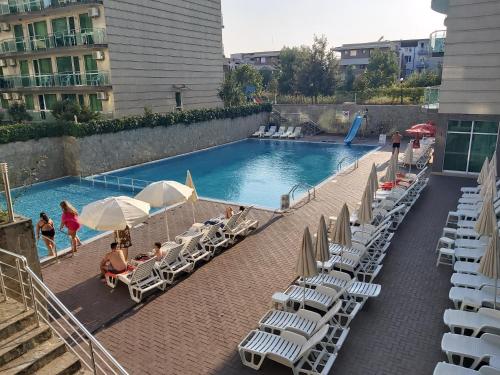 a swimming pool with lounge chairs and umbrellas and people at Clara Sea View in Burgas City