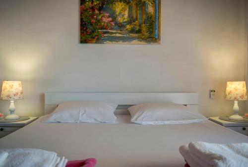 - un lit blanc avec deux lampes et une peinture murale dans l'établissement Vacation house near sea & beaches with HEATED POOL & BBQ, à Orebić
