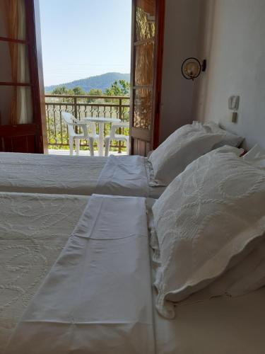 een bed met witte lakens en uitzicht op een balkon bij Hotel George in Chrysi Ammoudia