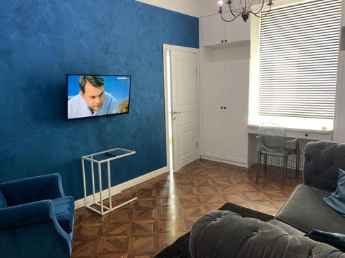 a living room with a couch and a tv on a blue wall at Квартира Титова 12 in Dnipro