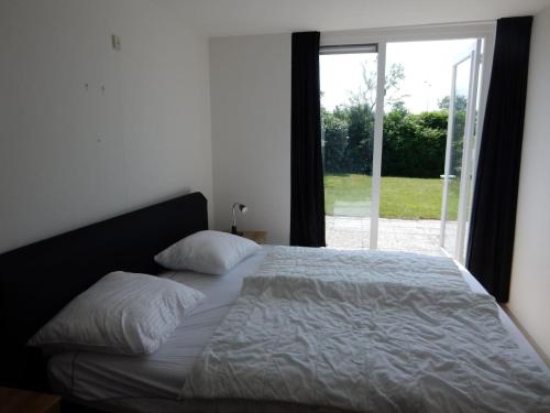 un letto in una camera da letto con una grande finestra di Ostrea 120 Kamperland a Kamperland