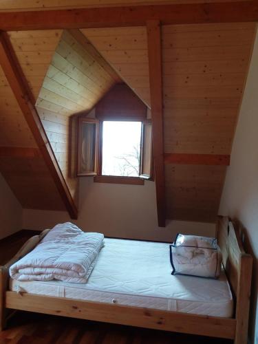 Łóżko w drewnianym pokoju z oknem w obiekcie Heavens Gate w mieście Saint-Pierre-de-Soucy