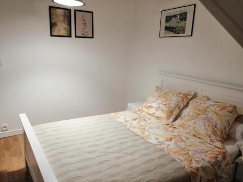 a bed in a bedroom with pictures on the wall at Chambres d'Hôtes Chez Marilou in Aulnay-sous-Bois