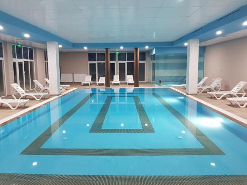 a large swimming pool with white chairs in a building at Апартаментен туристически комплекс Аква Терми in Krasnovo