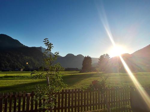 a sun setting over a field with a fence at Appartment Hirschberg in Bizau