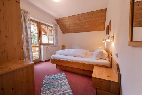 1 dormitorio con 1 cama en una habitación con paredes de madera en Ferienwohnung Dorfpub en Neustift im Stubaital